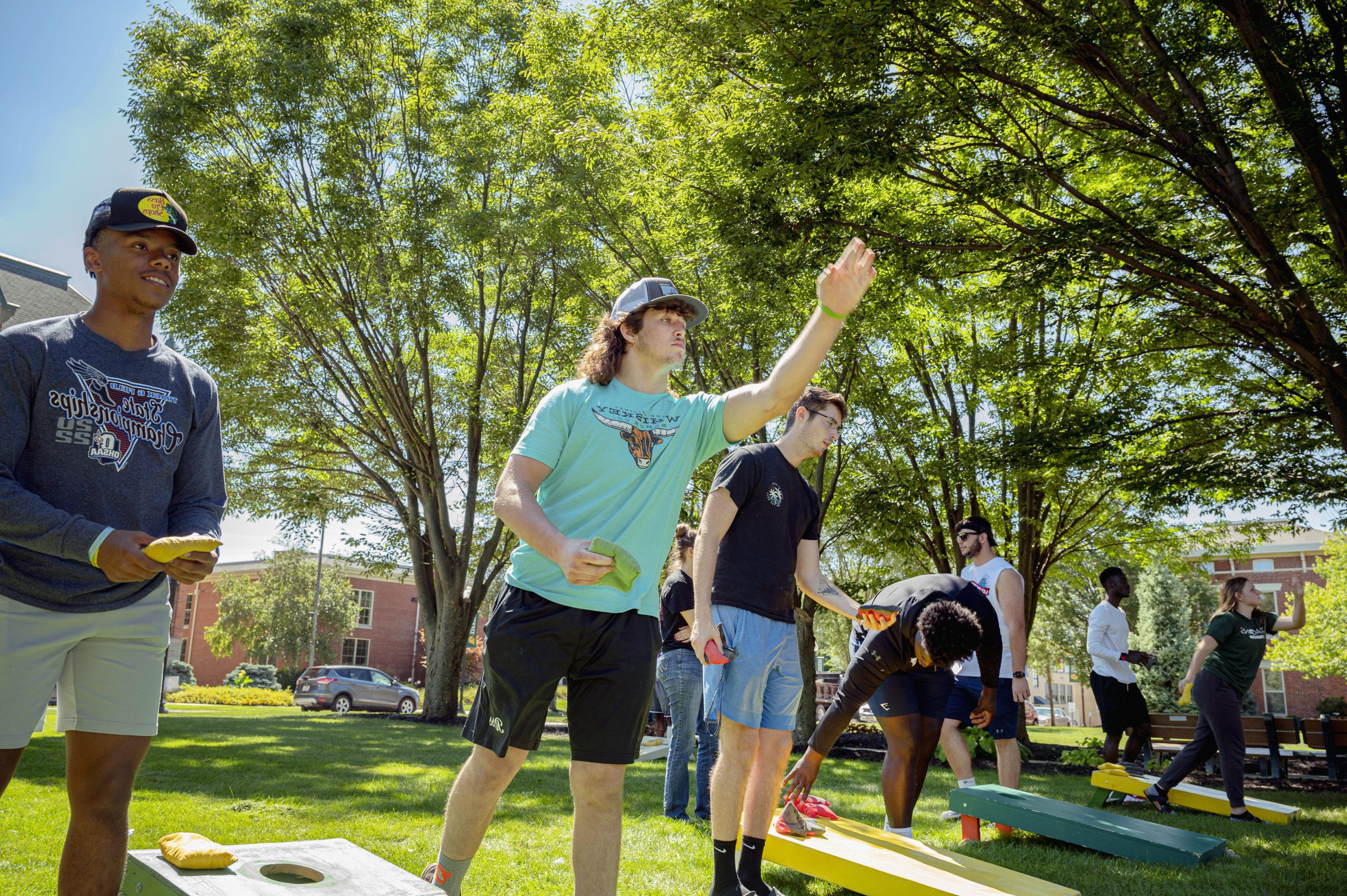 Group of students plays cornhole in the courtyard